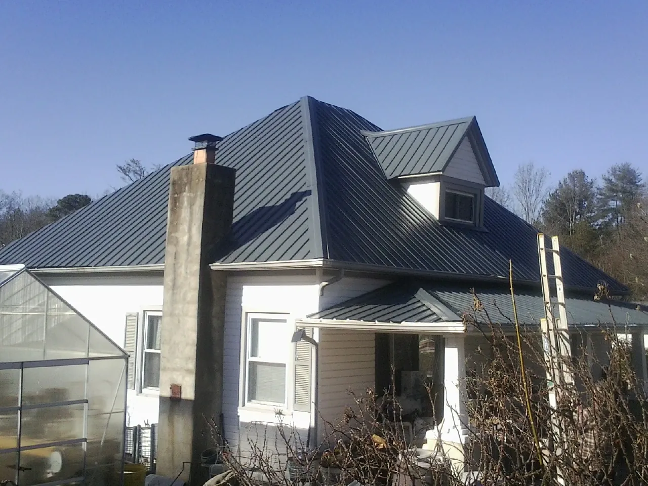 Dark blue standing seam metal roof on a white farmhouse with dormer — Slate & Tile Roof Repair by Roofing Brothers in Apollo