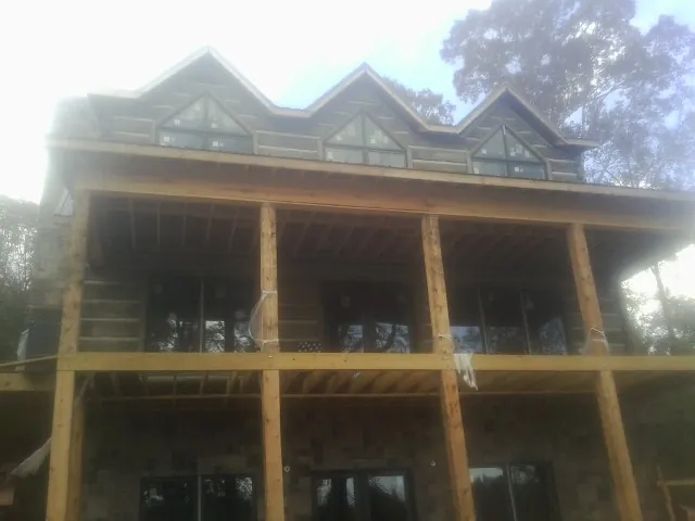 Dormers and porch framing on a large log home under construction — Roof Coating work by our crew in Apollo