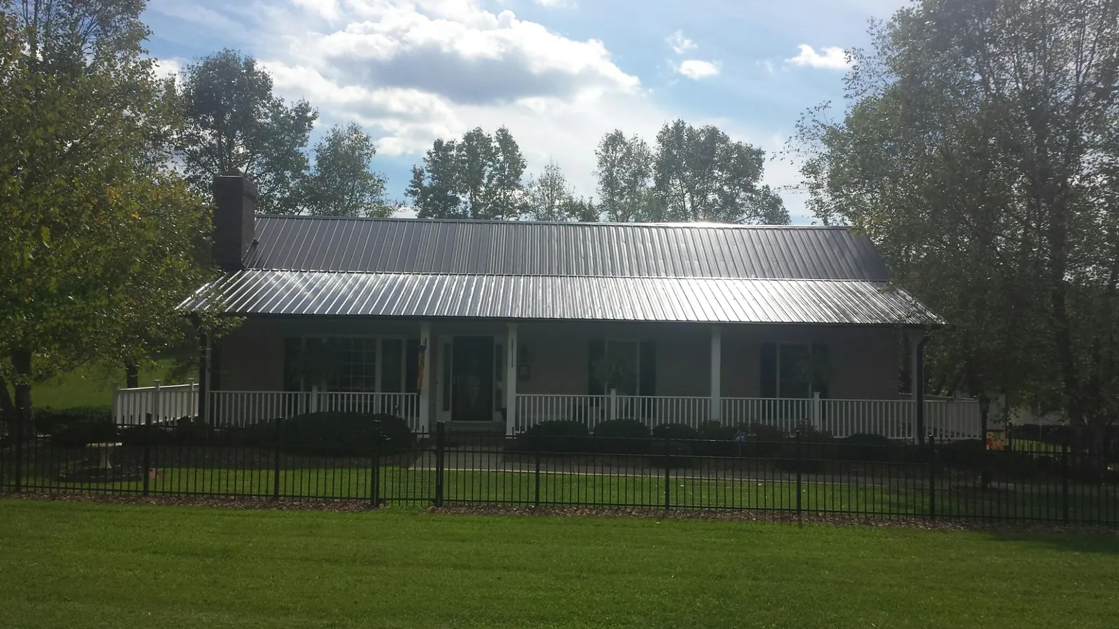 Gray metal roof on a brick ranch with a full width front porch — Gutter Guard Installation work by our crew in Apollo