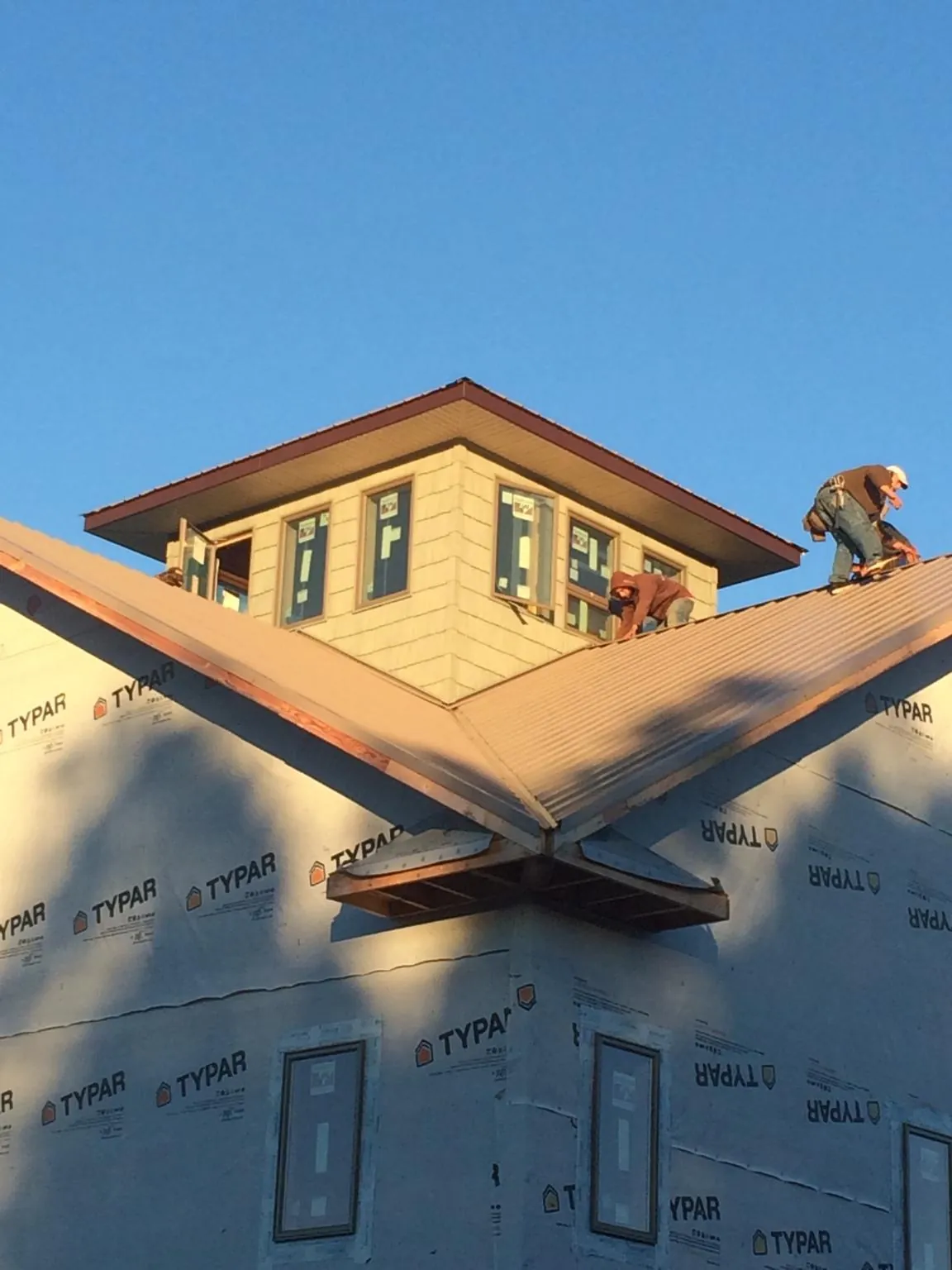 Roofers working around a rooftop cupola on a new metal roof at sunset — Roof Waterproofing in Apollo by Roofing Brothers